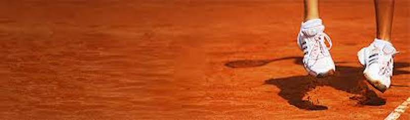 Person Playing Tennis on Clay Court